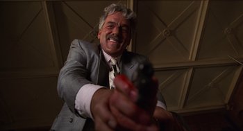 Movie still from “Get Shorty” (1995), directed by Barry Sonnenfeld – An older man in a suit and tie holding a gun; Close Up shot, Low angle