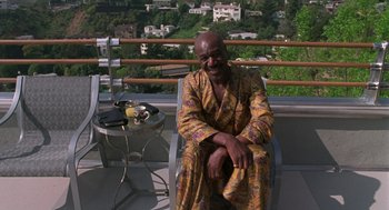 Movie still from “Get Shorty” (1995), directed by Barry Sonnenfeld – A man sitting on a chair on top of a balcony; Medium shot, High angle