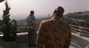 Movie still from “Get Shorty” (1995), directed by Barry Sonnenfeld – Two men standing on a balcony looking out at a city; Wide shot, Over the shoulder angle
