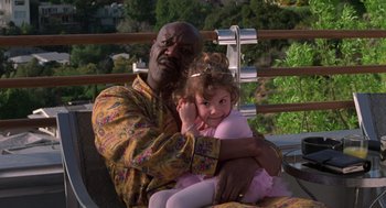 Movie still from “Get Shorty” (1995), directed by Barry Sonnenfeld – A man holding a little girl while sitting on his lap; Medium shot, Over the shoulder angle
