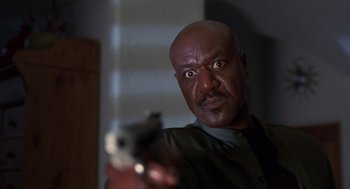 Movie still from “Get Shorty” (1995), directed by Barry Sonnenfeld – A man holding a gun in a room; Close Up shot, Low angle