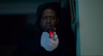 Movie still from “Ghost Dog: The Way of the Samurai” (1999), directed by Jim Jarmusch – A man in a black hoodie holding a red object; Close Up shot, High angle