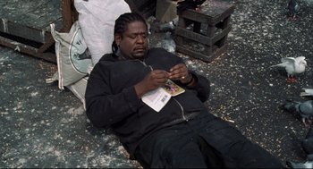 Movie still from “Ghost Dog: The Way of the Samurai” (1999), directed by Jim Jarmusch – A man sitting on the ground with a cell phone; Medium shot, High angle