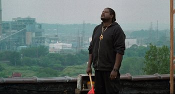 Movie still from “Ghost Dog: The Way of the Samurai” (1999), directed by Jim Jarmusch – A man standing on top of a building holding a guitar; Medium shot, Low angle