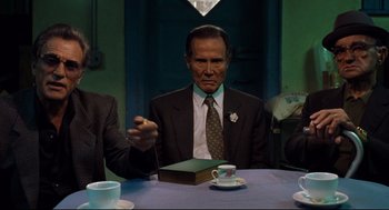 Movie still from “Ghost Dog: The Way of the Samurai” (1999), directed by Jim Jarmusch – An older man sitting at a table with a book; Medium shot, Over the shoulder angle