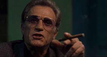 Movie still from “Ghost Dog: The Way of the Samurai” (1999), directed by Jim Jarmusch – An older man wearing glasses and holding a cigar; Close Up shot, Low angle