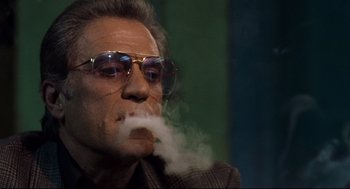 Movie still from “Ghost Dog: The Way of the Samurai” (1999), directed by Jim Jarmusch – An older man with glasses smoking a cigarette; Close Up shot, Low angle