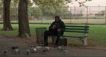 Movie still from “Ghost Dog: The Way of the Samurai” (1999), directed by Jim Jarmusch – A man sitting on a park bench with pigeons around him; Wide shot, Low angle