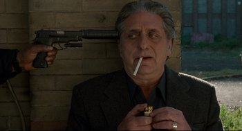 Movie still from “Ghost Dog: The Way of the Samurai” (1999), directed by Jim Jarmusch – An older man smoking a cigarette while holding a gun; Close Up shot, Over the shoulder angle