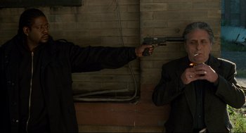 Movie still from “Ghost Dog: The Way of the Samurai” (1999), directed by Jim Jarmusch – A man holding a gun pointed at another man in a suit; Medium shot, Overhead angle