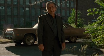 Movie still from “Ghost Dog: The Way of the Samurai” (1999), directed by Jim Jarmusch – An older man standing in front of an old car; Medium shot, Low angle