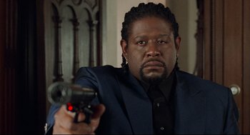 Movie still from “Ghost Dog: The Way of the Samurai” (1999), directed by Jim Jarmusch – A man in a suit and tie holding a gun; Close Up shot, Low angle