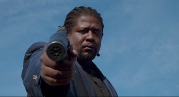 Movie still from “Ghost Dog: The Way of the Samurai” (1999), directed by Jim Jarmusch – A man holding a gun pointed at the sky; Close Up shot, Low angle