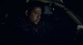 Movie still from “Ghost Dog: The Way of the Samurai” (1999), directed by Jim Jarmusch – A man sitting in the driver's seat of a car at night; Close Up shot, Low angle