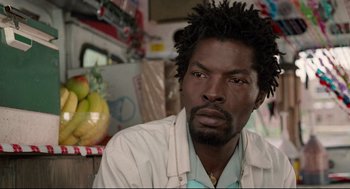 Movie still from “Ghost Dog: The Way of the Samurai” (1999), directed by Jim Jarmusch – A person sitting in front of fruit; Close Up shot, Low angle
