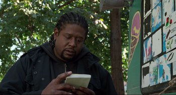 Movie still from “Ghost Dog: The Way of the Samurai” (1999), directed by Jim Jarmusch – A man with dreadlocks looking down at a book; Close Up shot, Low angle