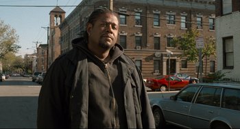 Movie still from “Ghost Dog: The Way of the Samurai” (1999), directed by Jim Jarmusch – A man standing in front of a building on a city street; Medium shot, Low angle
