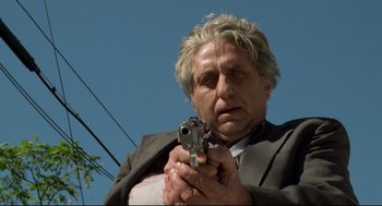 Movie still from “Ghost Dog: The Way of the Samurai” (1999), directed by Jim Jarmusch – An older man holding a gun while wearing a suit and tie; Close Up shot, Low angle