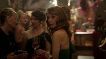 Movie still from “Emily in Paris” (2020), created by Darren Star – A woman in a green dress holding a glass of wine; Close Up shot, Over the shoulder angle