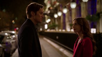 Movie still from “Emily in Paris” (2020), created by Darren Star – A man and a woman standing next to each other on a train platform; Medium shot, Over the shoulder angle