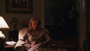 Movie still from “Ghosts of Mississippi” (1996), directed by Rob Reiner – A woman sitting in a chair in the dark; Medium shot, Over the shoulder angle