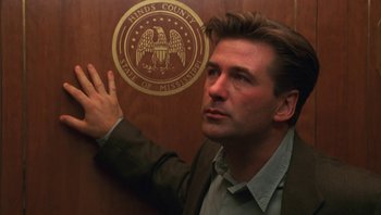 Movie still from “Ghosts of Mississippi” (1996), directed by Rob Reiner – A man standing in front of a wall with a seal on it; Close Up shot, Low angle