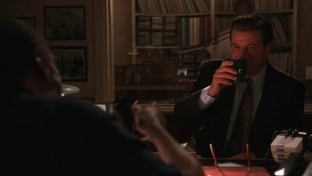 Movie still from “Ghosts of Mississippi” (1996), directed by Rob Reiner – A man sitting at a table looking at his cell phone; Medium shot, Over the shoulder angle