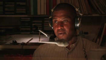 Movie still from “Ghosts of Mississippi” (1996), directed by Rob Reiner – A man wearing headphones and sitting in front of a microphone; Close Up shot, Low angle