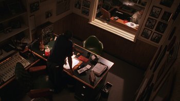 Movie still from “Ghosts of Mississippi” (1996), directed by Rob Reiner – A man sitting at a desk looking at papers on top of a desk; Wide shot, High angle