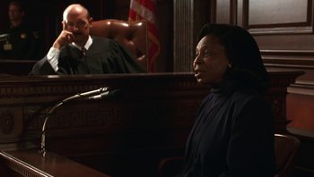Movie still from “Ghosts of Mississippi” (1996), directed by Rob Reiner – A woman sitting in front of a judge in a courtroom; Medium shot, Over the shoulder angle
