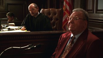 Movie still from “Ghosts of Mississippi” (1996), directed by Rob Reiner – A judge and a judge sitting in front of a microphone in a courtroom; Medium shot, High angle