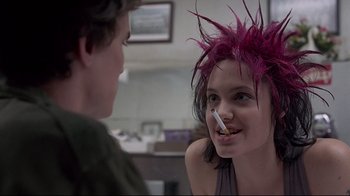 Movie still from “Gia” (1998), directed by Michael Cristofer – A woman with pink hair is smoking a cigarette; Close Up shot, Over the shoulder angle