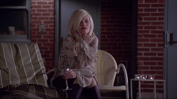 Movie still from “Gia” (1998), directed by Michael Cristofer – A woman sitting on a chair holding a glass of wine; Medium shot, High angle