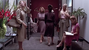 Movie still from “Gia” (1998), directed by Michael Cristofer – A group of women standing around each other in a room; Wide shot, Low angle