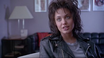 Movie still from “Gia” (1998), directed by Michael Cristofer – A person sitting on a couch; Close Up shot, Over the shoulder angle