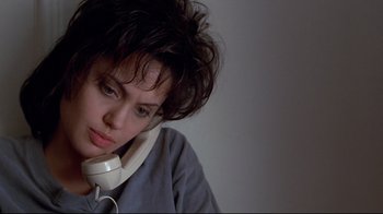 Movie still from “Gia” (1998), directed by Michael Cristofer – A young woman with headphones on her ears; Close Up shot, Low angle