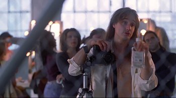Movie still from “Gia” (1998), directed by Michael Cristofer – A man with long hair is holding a camera; Medium shot, Low angle