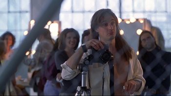 Movie still from “Gia” (1998), directed by Michael Cristofer – A man taking a picture with a camera on a tripod; Medium shot, Low angle