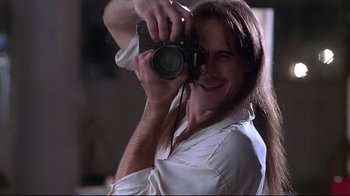 Movie still from “Gia” (1998), directed by Michael Cristofer – A man taking a picture with a camera; Close Up shot, Low angle