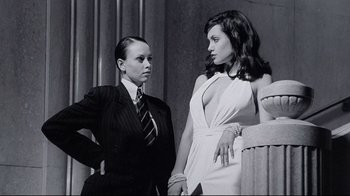 Movie still from “Gia” (1998), directed by Michael Cristofer – Two women standing next to each other in front of a pillar; Medium shot, Low angle