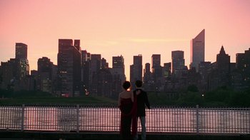 Two people standing on a bridge looking at a city skyline