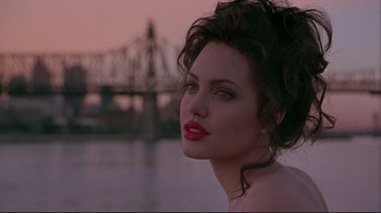 Movie still from “Gia” (1998), directed by Michael Cristofer – A beautiful woman with red lipstick standing next to a body of water; Close Up shot, Over the shoulder angle