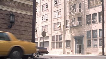Movie still from “Gia” (1998), directed by Michael Cristofer – A car driving down a street next to tall buildings; Extreme Wide shot, High angle