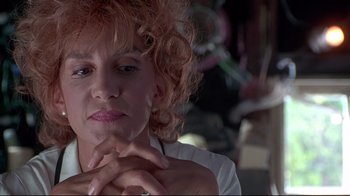 Movie still from “Gia” (1998), directed by Michael Cristofer – A person sitting with their hands crossed; Close Up shot, Low angle