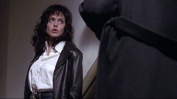 Movie still from “Gia” (1998), directed by Michael Cristofer – A woman wearing a black leather jacket looking at a mirror; Medium shot, Over the shoulder angle