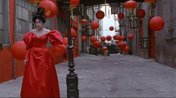 A woman in a long red dress standing next to a street lamp