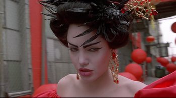 Movie still from “Gia” (1998), directed by Michael Cristofer – A woman in a red dress and a black hat; Close Up shot, Over the shoulder angle