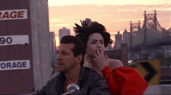 Movie still from “Gia” (1998), directed by Michael Cristofer – A man and a woman sitting next to each other on top of a building; Medium shot, Over the shoulder angle