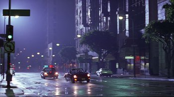 Movie still from “Gia” (1998), directed by Michael Cristofer – Cars driving down a street at night in the rain; Extreme Wide shot, Low angle