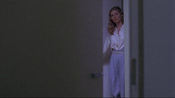 Movie still from “Gia” (1998), directed by Michael Cristofer – A woman standing in a doorway wearing a white shirt; Medium shot, Over the shoulder angle